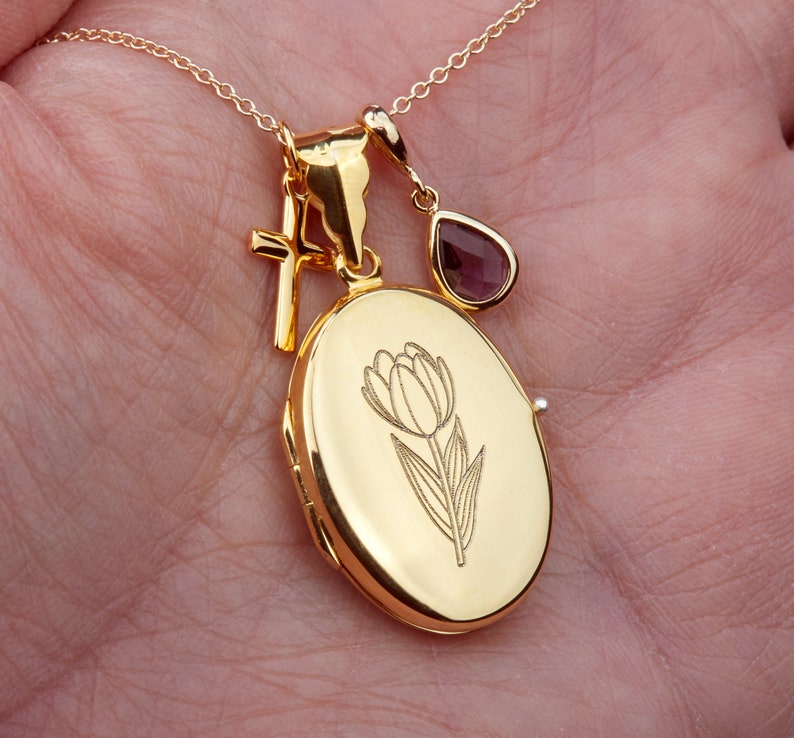 May include: Gold locket necklace with a tulip design, a small cross charm, and a purple gemstone pendant.