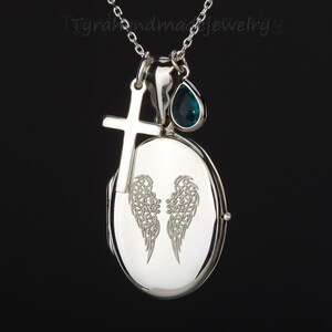 May include: Silver locket necklace with a cross charm and a teardrop-shaped blue gemstone. The locket features an engraved design of angel wings.