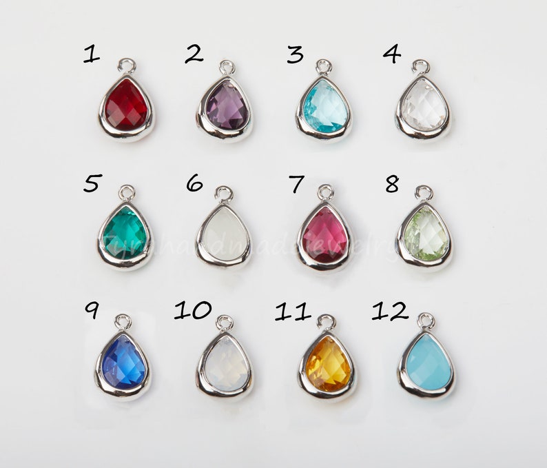 May include: Twelve teardrop-shaped glass charms with silver settings. The charms are numbered 1 through 12 and come in a variety of colors, including red, purple, blue, green, white, and yellow.