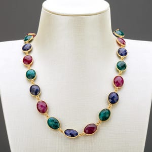 以下が含まれることがあります： 赤、緑、青の色合いの楕円形の宝石がついた金のチェーンネックレスです。