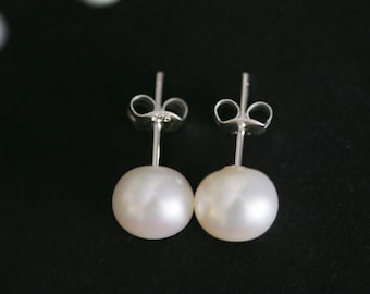 Puede incluir: Un par de pendientes de perlas con postes de plata. Las perlas son blancas y redondas.