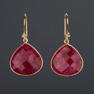 Pu&ograve; includere: Un paio di orecchini d'oro con pietre di rubino rosso a forma di goccia.
