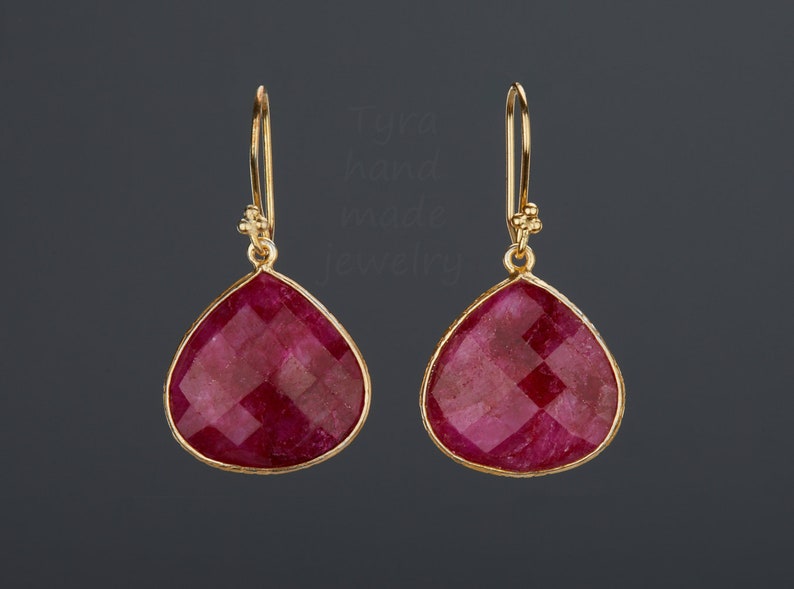 Pu&ograve; includere: Un paio di orecchini d'oro con pietre di rubino rosso a forma di goccia.