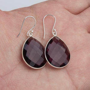 May include: A pair of sterling silver earrings with faceted amethyst teardrop stones.