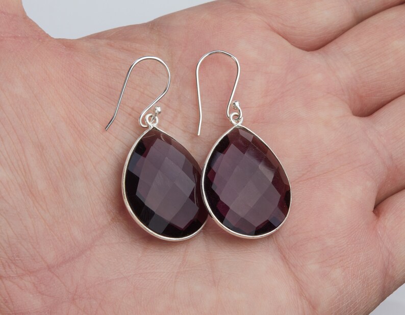 May include: A pair of sterling silver earrings with faceted amethyst teardrop stones.
