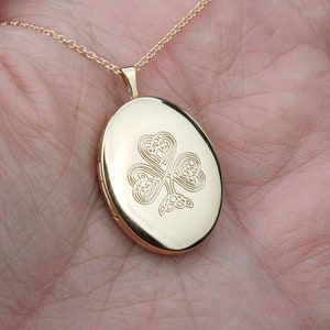 May include: Gold oval locket necklace with a Celtic knot shamrock design.