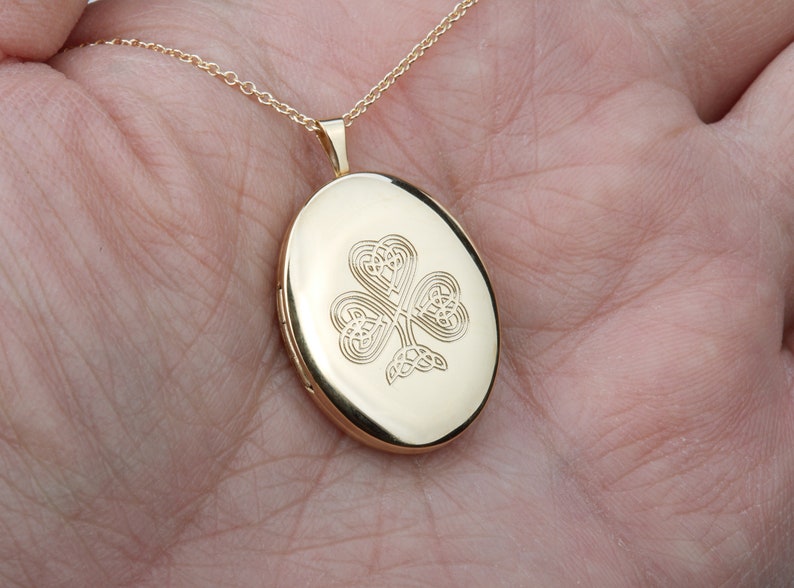 May include: Gold oval locket necklace with a Celtic knot shamrock design.