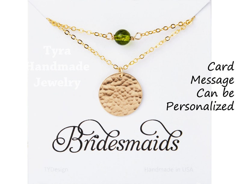 May include: A gold necklace with a hammered circle pendant and a green glass bead. The necklace is displayed on a white card with the text "Tyra Handmade Jewelry" and "Bridesmaids". The card also says "Card Message Can be Personalized".