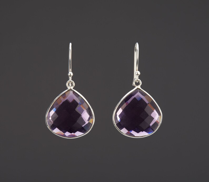 May include: A pair of silver dangle earrings with teardrop-shaped amethyst gemstones.