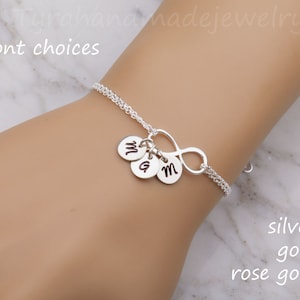 Könnte beinhalten: Silbernes Unendlichkeitsarmband mit drei kleinen Anhängern, die jeweils mit dem Buchstaben "M" graviert sind. Das Armband ist in Silber, Gold und Roségold erhältlich.