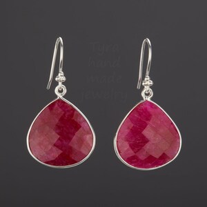 Pu&ograve; includere: Un paio di orecchini pendenti in argento con gocce di pietra preziosa rossa a forma di lacrima. Gli orecchini hanno un design sfaccettato.