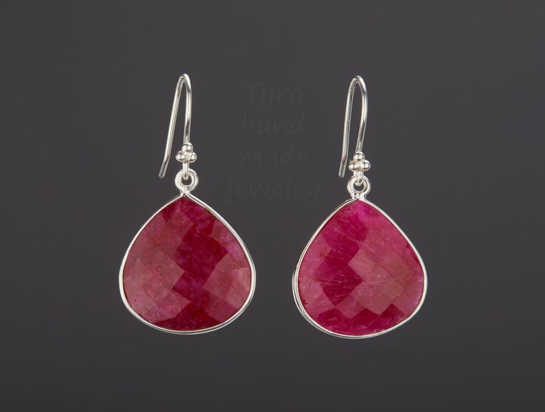 Pu&ograve; includere: Un paio di orecchini pendenti in argento con gocce di pietra preziosa rossa a forma di lacrima. Gli orecchini hanno un design sfaccettato.