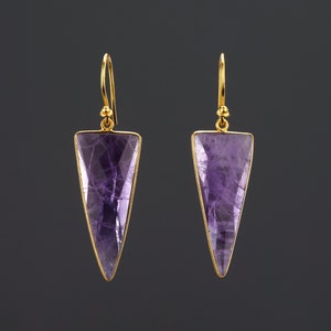 May include: A pair of gold earrings with purple amethyst triangle shaped stones.