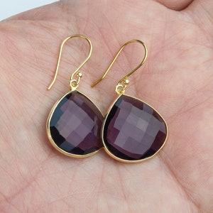 May include: A pair of gold dangle earrings with teardrop-shaped amethyst gemstones.