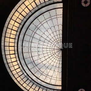 Peut inclure: Un plafond en verre en demi-cercle avec un motif géométrique de cercles et de carrés. Le plafond est en verre clair et est éclairé par la lumière naturelle.