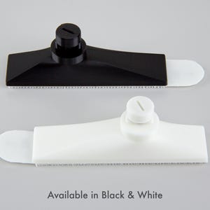 Pu&ograve; includere: Due tergivetri in plastica, uno nero e uno bianco, sono esposti su uno sfondo grigio. Ogni tergivetro ha un corpo rettangolare con un bordo strutturato e un'estremit&agrave; arrotondata. Il testo "Available in Black & White" &egrave; in basso.