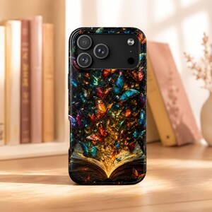 May include: A black smartphone case featuring a vibrant, magical design of an open book with glowing golden light emanating from its pages, surrounded by a swarm of colorful butterflies in shades of blue, orange, and purple against a dark background.