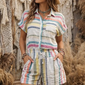 Könnte beinhalten: Ein gestreiftes Leinen-Shirt und Shorts-Set in Pastellfarben. Das Shirt hat kurze Ärmel und eine Knopfleiste, kombiniert mit passenden Shorts mit Kordelzug. Ein Strohhut und mehrschichtige Halsketten vervollständigen den Look.