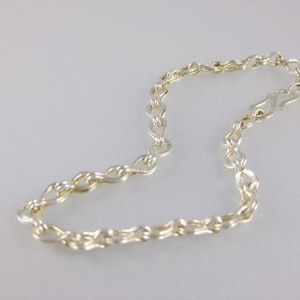 May include: A silver chain necklace with a twisted design.