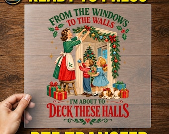 May include: A DTF transfer sheet featuring a vintage-style illustration of a person in a green dress and red apron decorating a doorway with garland. Two children and a dog are nearby with Christmas gifts. Text reads: FROM THE WINDOWS TO THE WALLS I'M ABOUT TO DECK THESE HALLS.