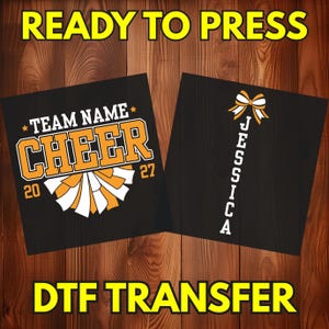 May include: A black DTF transfer sheet featuring two designs. The left design displays the text TEAM NAME CHEER with the year 2027 and a pom-pom graphic in orange and white. The right design shows the name JESSICA vertically with a hair bow graphic.