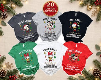 May include: Six short-sleeved t-shirts in dark grey, light grey, black, green, white, and red. Each shirt features a Disney character graphic, Christmas icons, and text including 'Most Likely To' followed by phrases like 'Spread Christmas Joy'.