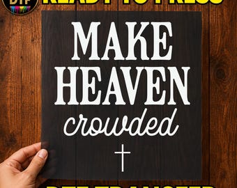 May include: A square DTF transfer sheet featuring the white text "MAKE HEAVEN crowded" in a combination of bold serif and cursive script fonts, with a small white cross symbol centred below the text on a transparent background.
