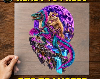 May include: A DTF transfer sheet featuring a colourful illustration of a fluffy cat wearing a crown and purple sunglasses, riding a blue and pink feathered dinosaur. The scene includes a large purple moon, floating stone ruins, and waterfalls.