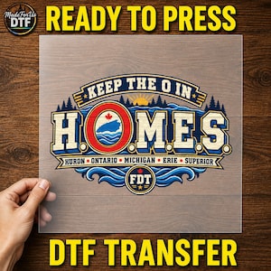 May include: A DTF transfer sheet featuring a graphic design with the text KEEP THE O IN HOMES. The design includes a red circle with a maple leaf, blue waves, a sun, and the names of the Great Lakes: HURON, ONTARIO, MICHIGAN, ERIE, SUPERIOR.