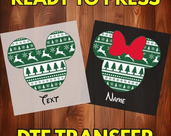 May include: Two DTF transfers featuring mouse-shaped silhouettes with a green and white holiday pattern of reindeer, pine trees, and snowflakes. One silhouette includes the word TEXT, and the other features a red bow and the word Name.