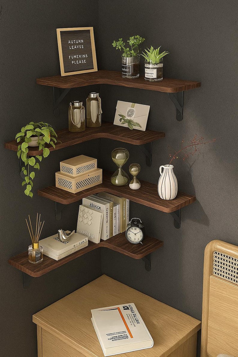 May include: A dark wood corner shelf unit with black metal brackets, displaying decorative items. The shelves hold plants, books, vases, and a small clock. A framed sign reads "Autumn Leaves, Fumekins Please."
