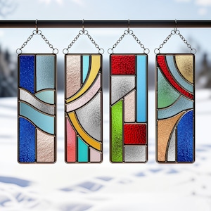 May include: Four rectangular stained glass panels with geometric designs. Each panel features a different color scheme, including blue, red, yellow, and green, with textured glass and dark metal frames. The panels hang from chains.