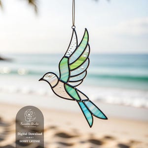 May include: Stained glass bird in flight, featuring shades of white, green, and blue. The bird has a black outline and is suspended by a thin wire. The image includes the text "Favorite Studio Creations" and "Digital Download, Hobby License."