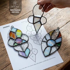 Puede incluir: Tres adornos de vidrieras de varias formas y colores, incluyendo una flor y un óvalo. Los adornos están sobre una superficie de madera con un patrón impreso y el texto "Digital Download HOBBY LICENSE".