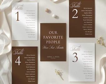 May include: A collection of wedding table cards and a sign. The cards are white and brown with guest names and table numbers. The sign reads "Our Favorite People, Your Seat Awaits" with names and a date. Ribbons and small flowers are arranged around the cards.