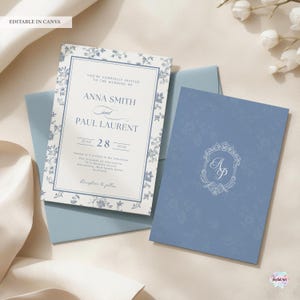 K&ouml;nnte beinhalten: Eine Hochzeitseinladungssuite in Blau und Wei&szlig; mit floralen Details. Die Einladungskarte zeigt die Namen "Anna Smith" und "Paul Laurent" sowie das Datum "28. Juni 2026". Die Suite umfasst auch einen passenden Umschlag und eine Karte mit einem Monogramm.