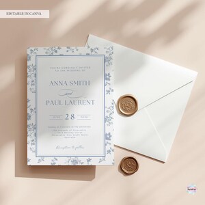 K&ouml;nnte beinhalten: Eine Hochzeitseinladungssuite mit einem blau-wei&szlig;en Blumendesign. Die Einladung enth&auml;lt die Namen Anna Smith und Paul Laurent, das Datum 28. Juni 2028 und Details zur Veranstaltung. Ein wei&szlig;er Umschlag und zwei goldene Wachssiegel sind ebenfalls vorhanden.