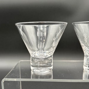 Peut inclure: Deux verres &agrave; martini en verre transparent avec un pied &eacute;pais. Le pied d'un verre porte l'inscription "Tanqueray" grav&eacute;e.