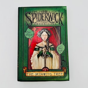 Puede incluir: Un libro de tapa dura titulado "The Spiderwick Chronicles: The Ironwood Tree". La portada presenta un retrato de una mujer sosteniendo una espada, sobre un fondo rojo. El libro tiene un borde verde con los nombres de los autores.