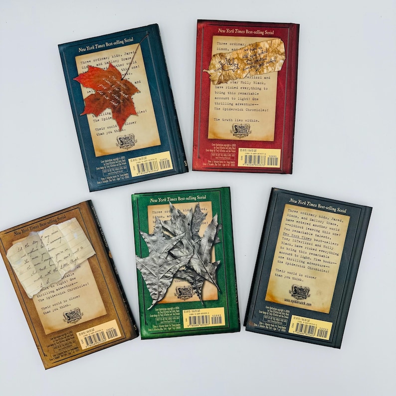 Puede incluir: Se muestran cinco libros con cubiertas de diferentes colores. Cada libro tiene un dise&ntilde;o &uacute;nico, que incluye una hoja roja, un trozo de pergamino y hojas plateadas. El texto en las cubiertas dice "New York Times Best-selling Serial."