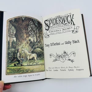 Puede incluir: Un libro abierto con ilustraciones y texto. La p&aacute;gina izquierda presenta un dibujo detallado de una persona arrodillada frente a un unicornio en un bosque. La p&aacute;gina derecha muestra el t&iacute;tulo "The Spiderwick Chronicles: Lucinda's Secret" y los nombres de los autores.