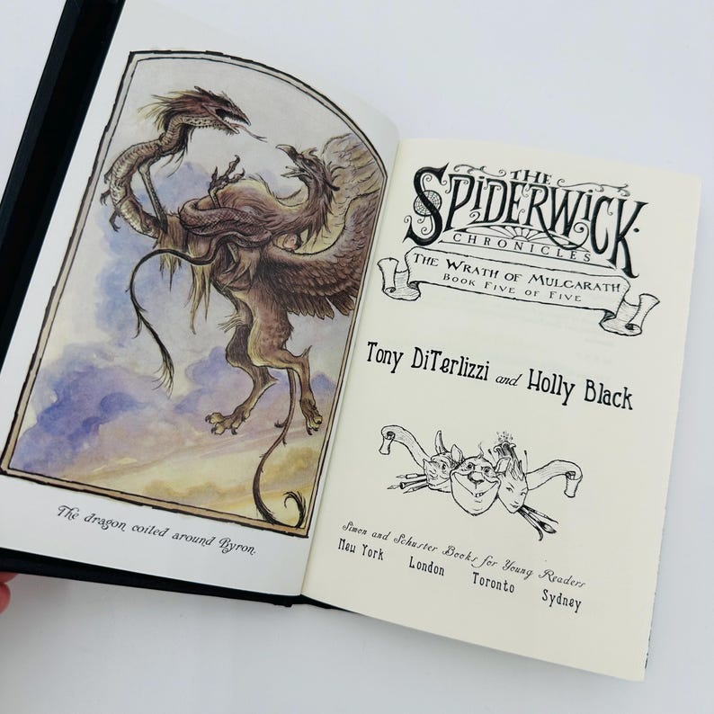 Puede incluir: Libro abierto con una cubierta negra. La ilustraci&oacute;n muestra un drag&oacute;n y un grifo. El texto dice "The Spiderwick Chronicles: The Wrath of Mulgarath, Book Five of Five" por Tony DiTerlizzi y Holly Black.