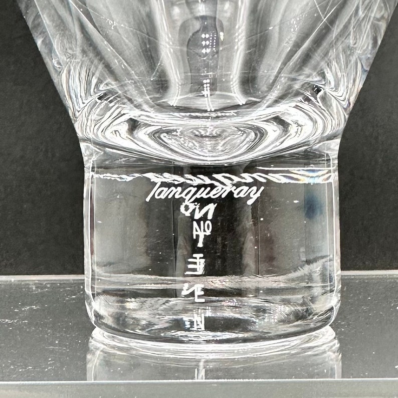 Peut inclure: Une bouteille en verre transparente &agrave; large ouverture et &agrave; surface textur&eacute;e. La bouteille est remplie d'un liquide clair et porte l'inscription "Tanqueray Gin No. Ten" grav&eacute;e sur le c&ocirc;t&eacute;.