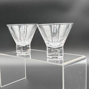 Peut inclure: Deux verres &agrave; martini en verre transparent avec un motif textur&eacute; et le mot "Tangueray" grav&eacute; au fond. Les verres sont pos&eacute;s sur un pr&eacute;sentoir en acrylique transparent.