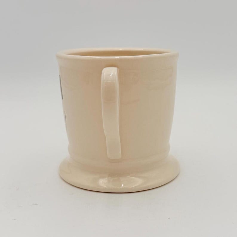 Puede incluir: Una taza de cer&aacute;mica color crema con base redondeada y asa curva. La taza tiene un dise&ntilde;o sencillo y cl&aacute;sico, apto para caf&eacute; o t&eacute;. La taza est&aacute; limpia y parece sin usar.