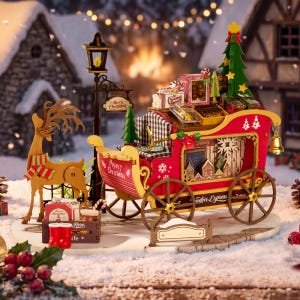 May include: A wooden Reindeer Express sleigh model featuring a red and yellow frame, a green Christmas tree, gift boxes, and a reindeer figure. The sleigh is decorated with Merry Christmas text, a gold bell, and a black street lamp.