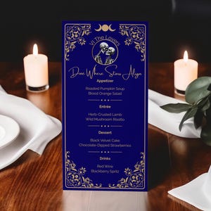 May include: A dark blue menu with gold filigree and the text "VI The Lovers" and "Dine Where Stars Align". The menu lists appetizers, entrees, desserts, and drinks. Two lit candles flank the menu on a wooden table.