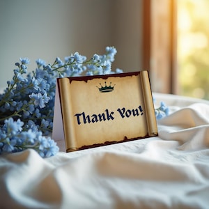 May include: A thank you card with a scroll design, featuring the words "Thank You!" in a dark blue font, topped with a green crown. The card is set against a backdrop of blue flowers and a white cloth.