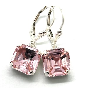 May include: A pair of leverback earrings featuring square, light pink gemstones. The gemstones are set in a silver-colored metal. The earrings are displayed against a white background.