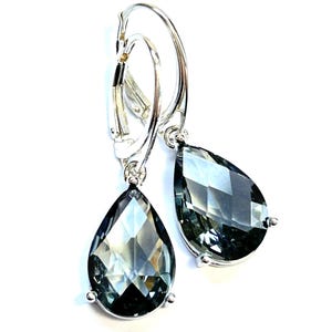 May include: A pair of silver-toned earrings with teardrop-shaped, faceted, smoky gray gemstones. The earrings have a lever-back closure and are set against a white background. The gemstones are approximately 1 inch in length.